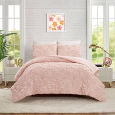 a bed with pink comforter and pillows in a room