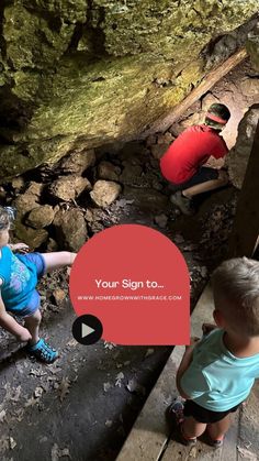 two young boys are climbing up stairs in a cave with a red sign that says your sign to