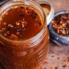 a jar filled with liquid sitting on top of a table next to a bowl of food