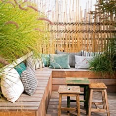 a wooden bench sitting on top of a wooden deck next to tall grass and plants