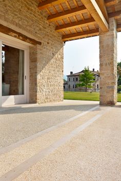 an outdoor patio with stone pillars and doors leading to the front door, surrounded by grass