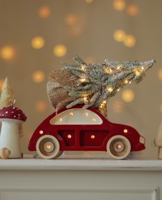 a red toy car with a christmas tree on top and mushrooms in the back ground