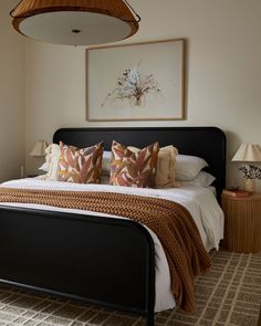 a bedroom with a bed, lamps and pictures on the wall above it's headboard