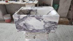 a marble sink in the middle of a room with paint and other items around it