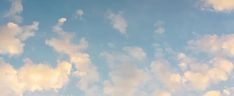 an airplane is flying through the blue sky with white clouds in the foreground,