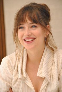 a woman smiling and wearing a white shirt