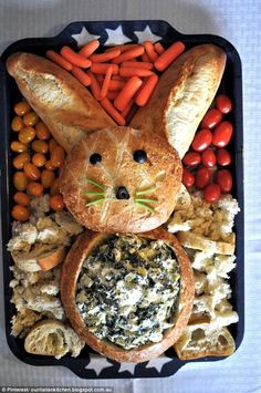 a bunny made out of bread, carrots and other food items on a tray