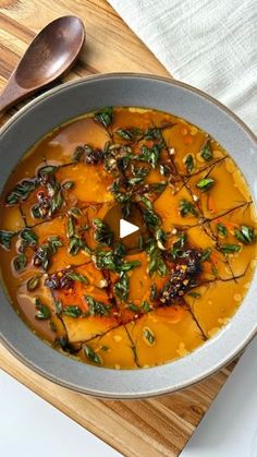 a bowl filled with soup on top of a wooden cutting board next to a spoon