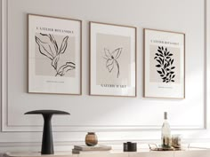 three black and white art prints hanging on the wall above a buffet with wine bottles