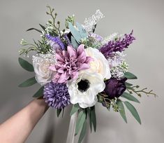 a bouquet of flowers is being held up by someone's hand on a gray background