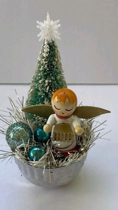 a tinker angel figurine sitting on top of a basket filled with ornaments