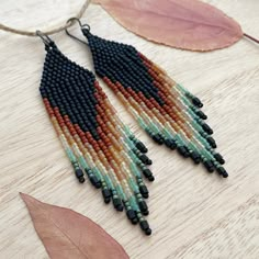 Reminiscent of the desert landscape with rich earthy terra cotta oranges, cream, jade and sage greens on a matte black background these long handwoven beaded earrings are a unique pallet and stunning on. Heavy gauge niobium ear wires  are sturdy and hypoallergenic.  1" wide x 3.75" long from the top of the ear wire to the tip of the longest fringe. Matte Black Background, Seed Bead Fringe Earrings, Seed Bead Jewelry Patterns, Beadwork Patterns, Bead Loom Patterns, Desert Landscape, Loom Patterns, Beaded Fringe, Seed Bead Earrings