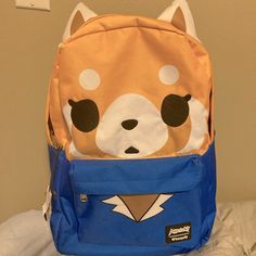 a small backpack with a dog face on the front and back pocket, sitting on a bed