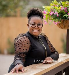 a woman sitting on a wooden bench next to a potted plant and smiling at the camera