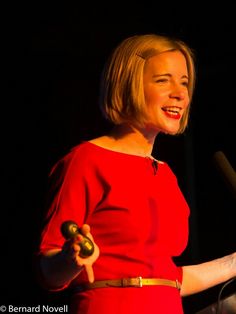 a woman in a red dress is giving a speech