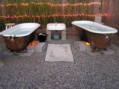 an outdoor bathtub and toilet in a graveled area with lights on the fence