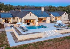 an aerial view of a house with a swimming pool and patio area at night time