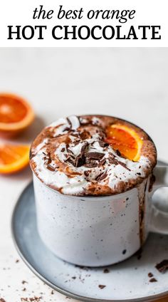 an orange hot chocolate in a mug with whipped cream on top, garnished with fresh orange slices