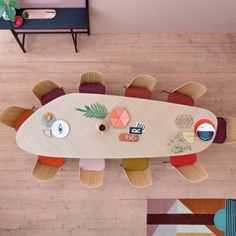 an overhead view of a dining room table with chairs and colorful rugs on the floor