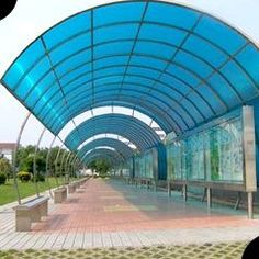 an empty walkway with benches under a blue awning