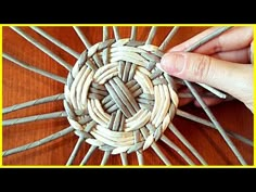 a person is making a woven object out of wood sticks and paper straws on a wooden table