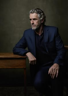 an older man in a suit sitting at a table