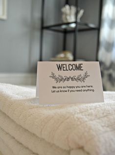 a welcome sign is placed on top of folded towels