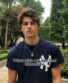 a young man is standing in front of some bushes and trees with the words what girls my age find attractive