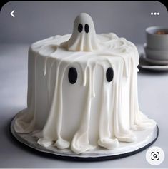 a cake with white icing and black eyes on it's face is decorated like a ghost