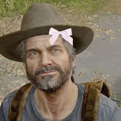 a man wearing a hat with a pink bow on it's head is standing in the woods