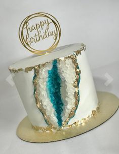 a white and blue birthday cake with gold trim