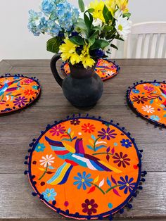 the table is set with four place mats and a vase full of flowers on it