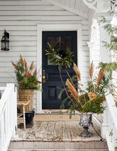 the front porch is decorated with wreaths and plants