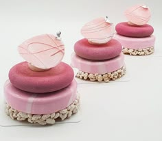 three cakes with pink frosting and decorative decorations