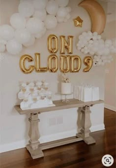 a table topped with balloons and cake next to a sign that says on cloud 9