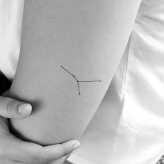 a woman's arm with a small zodiac sign tattoo on the left side of her arm