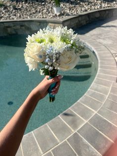 a person holding a bouquet of flowers in front of a swimming pool