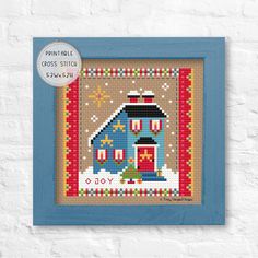 a blue frame with a cross stitch pattern on it that says,'christmas cottage '