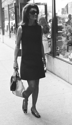 a woman walking down the street with a purse and handbag in her other hand