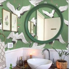 a bathroom with green wallpaper and white birds painted on the wall above the sink