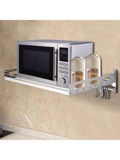 a microwave oven mounted on a wall with two spice jars in front of the microwave