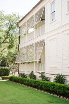 an apartment building with many balconies on the front and second story, along side a green lawn