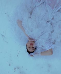 a woman is laying in the snow wearing a white dress