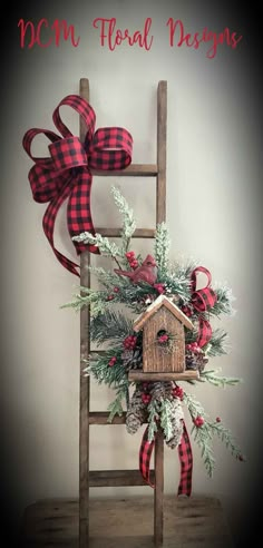 a wooden ladder with a birdhouse on it and red ribbon tied around the top