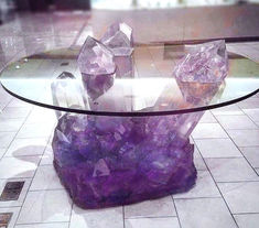 a glass table topped with purple rocks on top of a white tiled floor next to a window