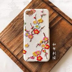 an iphone case with flowers on it sitting on top of a wooden tray next to a chinese writing