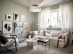 a living room filled with lots of furniture and pictures on the wall next to a window