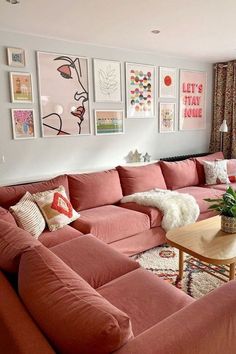 a living room with pink couches and pictures on the wall