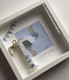 a white box with some blue buttons and a bunny on the inside is holding a card