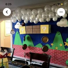 a room decorated with balloons and decorations for mario's birthday party on the wall